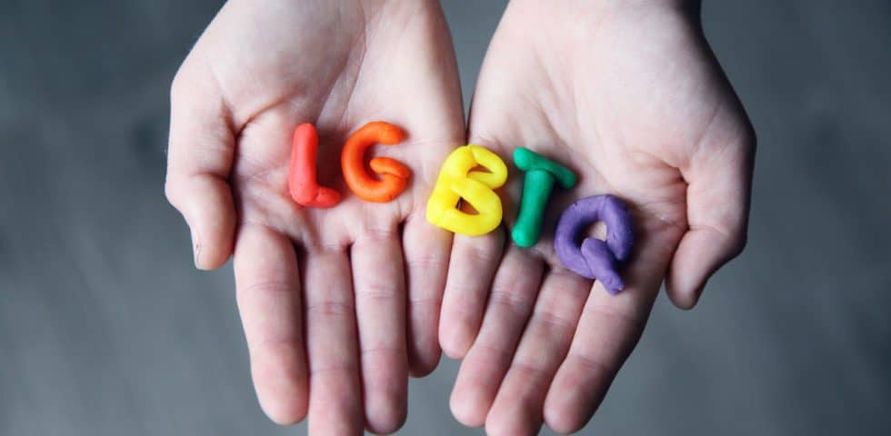 Hands with colorful letters spelling out LGBTQ