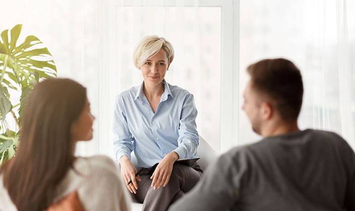 Therapist meets with married couple in cozy office.